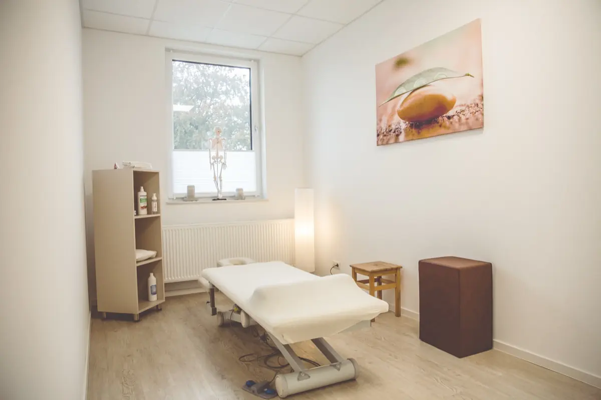 Behandlungsraum mit Therapieliege und Naturkunst